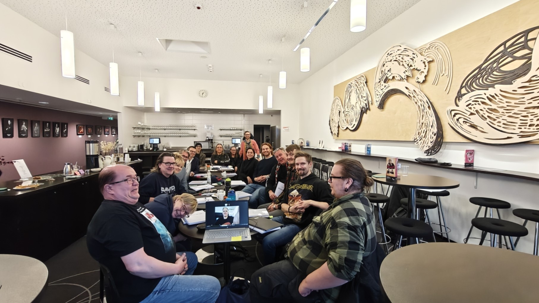 Näyttelijöitä pitkän pöydän ääressä.