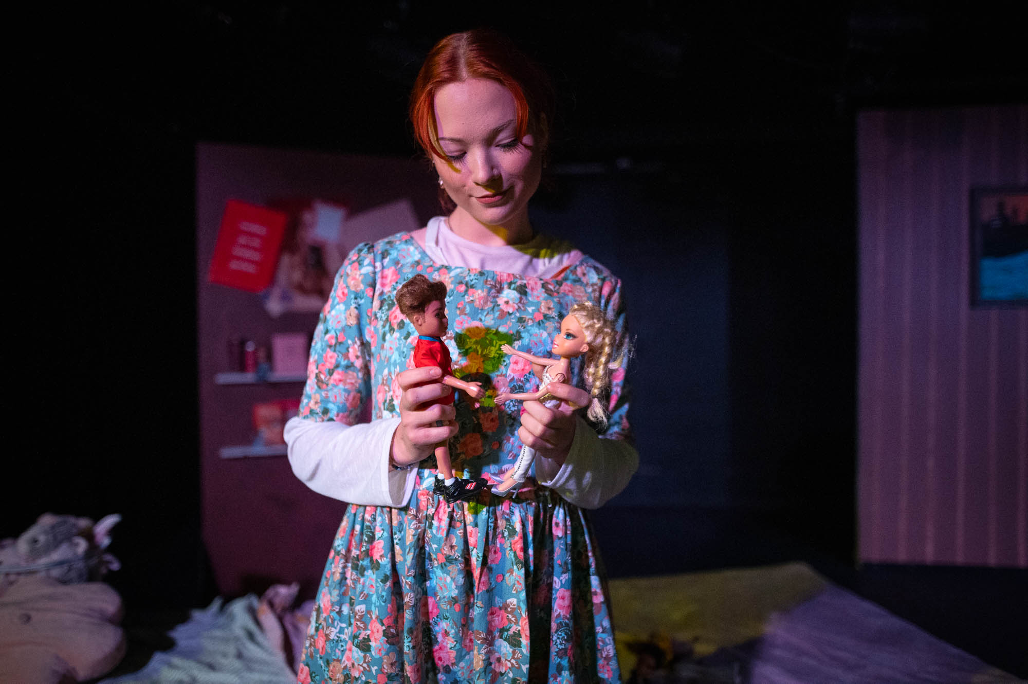 Tyttö seisoo lavalla ja hän pitelee käsissään kahta Barbie-nukkea.